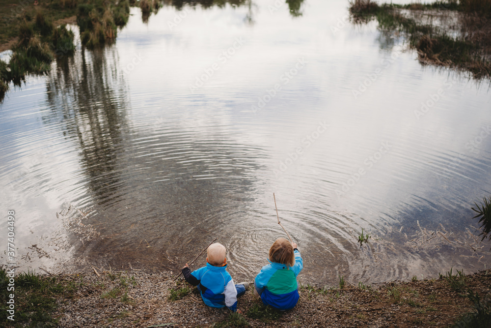 Back view of young kids in front of a lake in a park on cloudy day Back view of young kids in front of a lake in a park on cloudy day