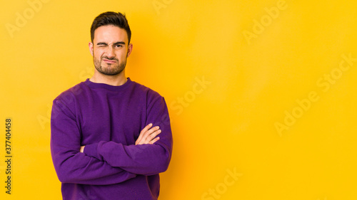 Young caucasian man isolated on yellow bakground unhappy looking in camera with sarcastic expression.