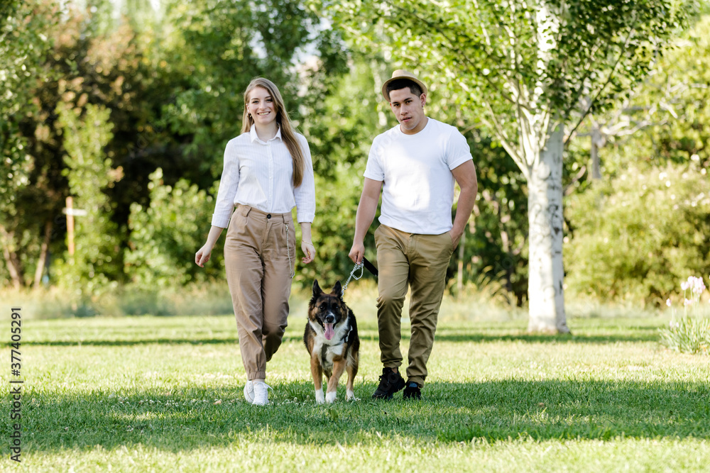 Young and modern couple walking and playing with their dog Border Collie in a park Young and modern couple walking and playing with their dog Border Collie in a park