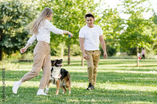Couple playing with their dog in the park. Latino man and Caucasian woman with a Border collie