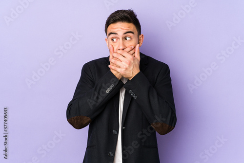 Young caucasian man isolated on purple background thoughtful looking to a copy space covering mouth with hand.