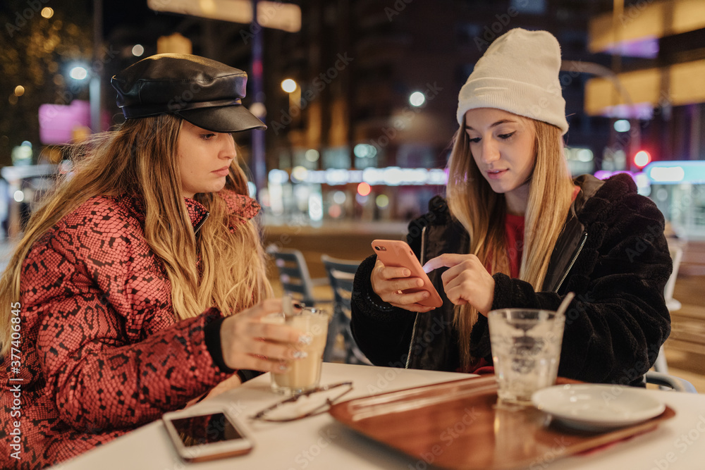 Two friends drinking coffee at night, on a terrace in the city, in autumn. Two friends drinking coffee at night, on a terrace in the city, in autumn.