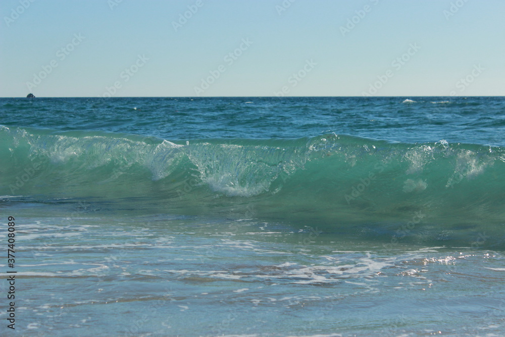 Transparent blue sea wave running to the shore with a crest