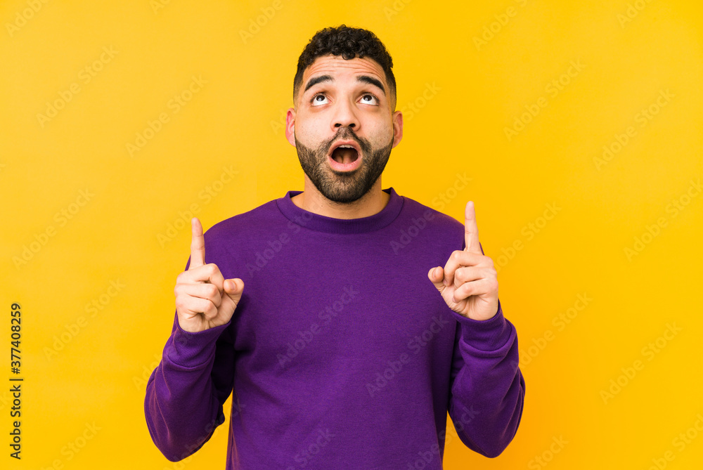 Young mixed race arabic man isolated pointing upside with opened mouth. Young mixed race arabic man isolated pointing upside with opened mouth.