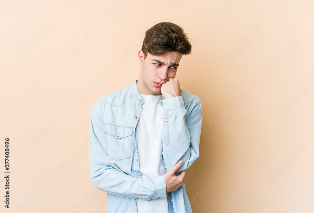 Young caucasian man isolated on beige background who feels sad and pensive, looking at copy space. Young caucasian man isolated on beige background who feels sad and pensive, looking at copy space.