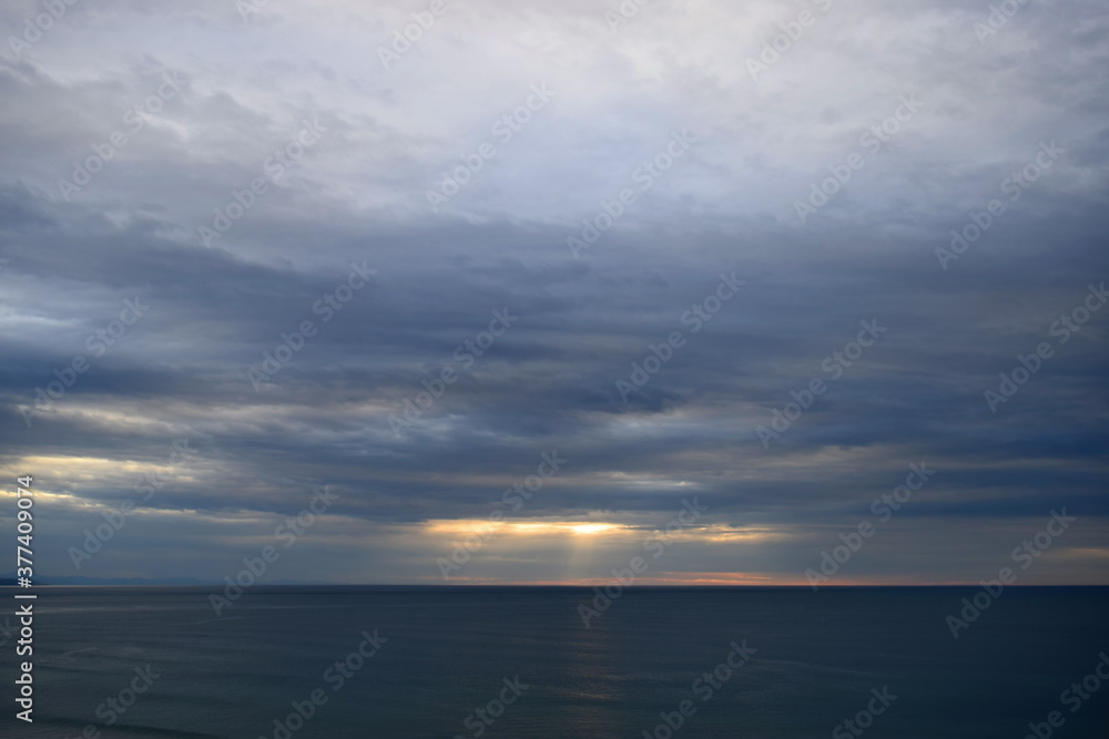 Dramatic and intense clouds over the sea with rays of sunset light