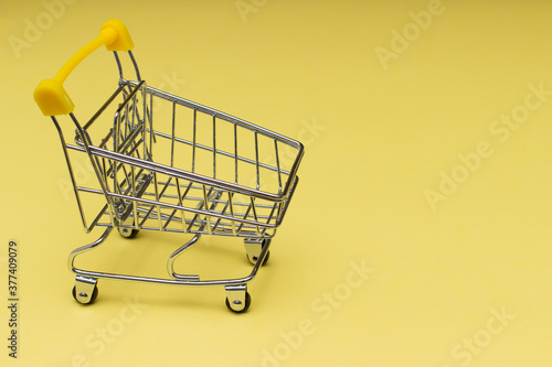 Shopping cart on yellow background, buy and sale concept.