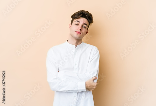 Young caucasian man isolated on beige background who is bored, fatigued and need a relax day.