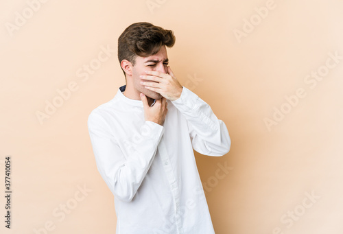 Young caucasian man isolated on beige background suffers pain in throat due a virus or infection.