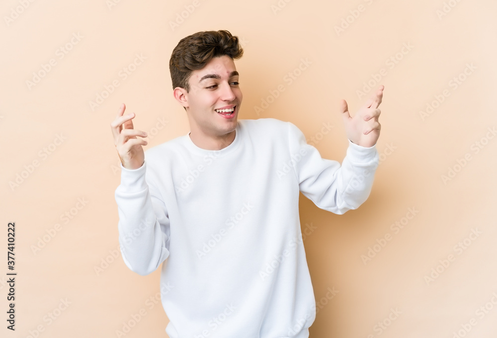 Young caucasian man isolated on beige background joyful laughing a lot. Happiness concept.
