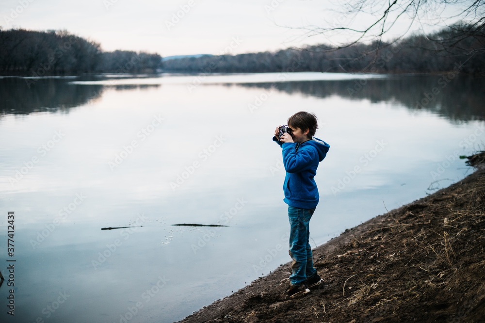 Boy taking photographs while exploring the river Boy taking photographs while exploring the river