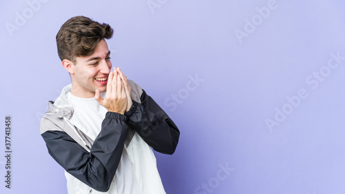 Young caucasian man isolated on purple background laughing about something, covering mouth with hands.