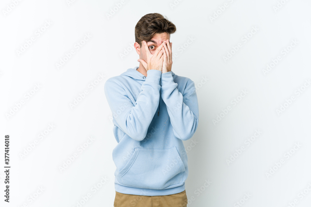 Young caucasian man isolated on white background blink through fingers frightened and nervous. Young caucasian man isolated on white background blink through fingers frightened and nervous.