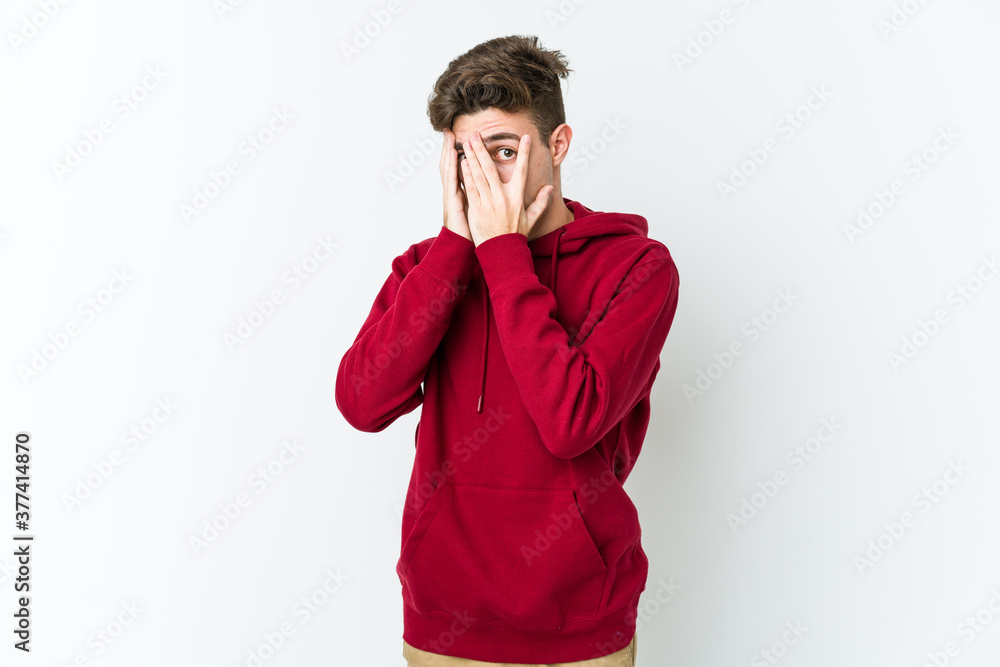Young caucasian man isolated on white background blink through fingers frightened and nervous. Young caucasian man isolated on white background blink through fingers frightened and nervous.
