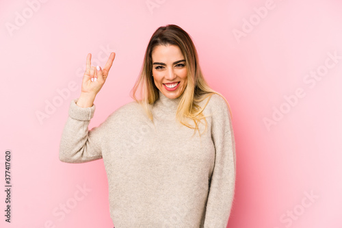 Middle age woman over isolated background showing a horns gesture as a revolution concept.