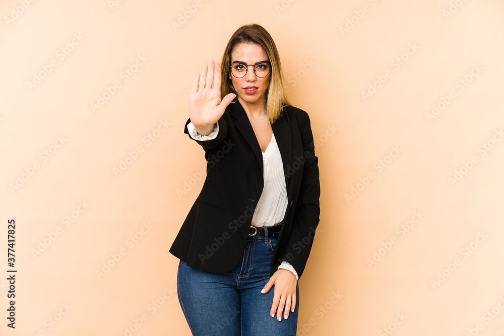 Middle age business woman isolated on beige background standing with outstretched hand showing stop sign, preventing you. Middle age business woman isolated on beige background standing with outstretched hand showing stop sign, preventing you.
