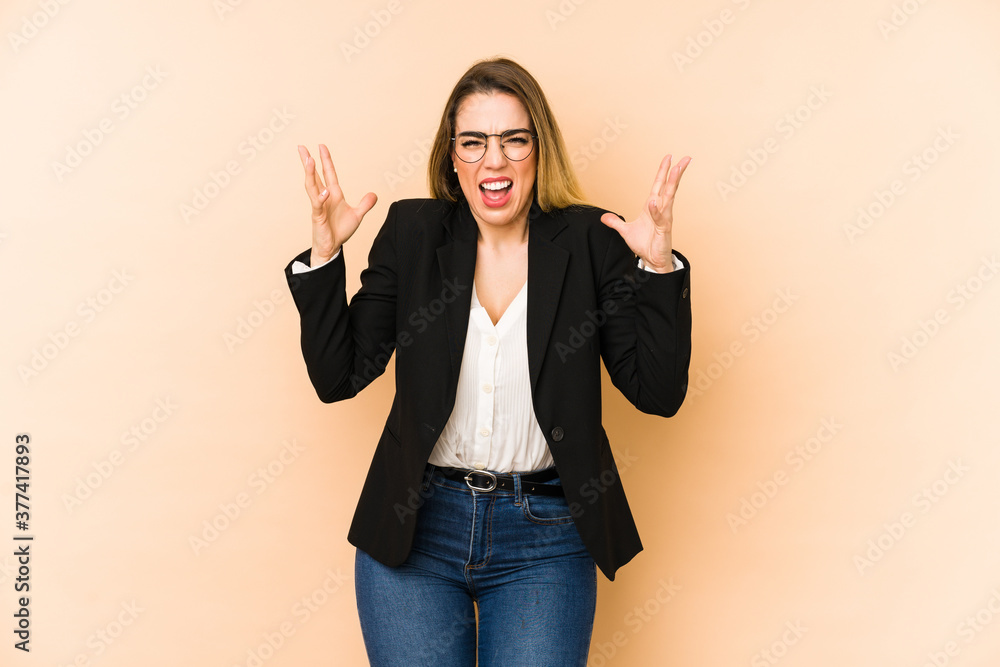 Middle age business woman isolated on beige background screaming with rage. Middle age business woman isolated on beige background screaming with rage.