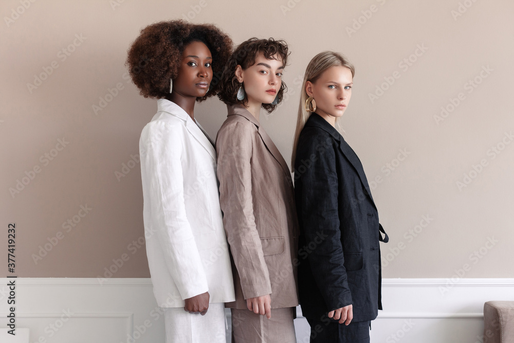 A small group of fashion multiracial multiethnic young beautiful sensual models are posing near the wall in studio room