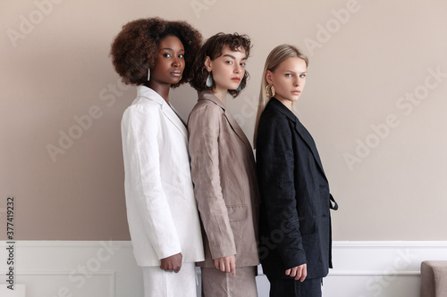 A small group of fashion multiracial multiethnic young beautiful sensual models are posing near the wall in studio room photo