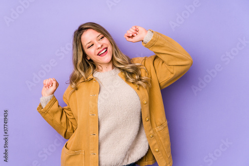 Young caucasian woman isolated on purple background celebrating a special day, jumps and raise arms with energy. © Asier
