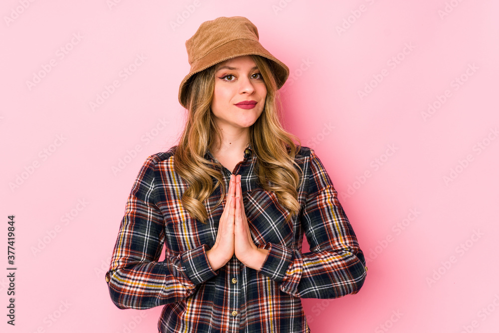 Young caucasian woman wearing a hat isolated praying, showing devotion, religious person looking for divine inspiration. Young caucasian woman wearing a hat isolated praying, showing devotion, religious person looking for divine inspiration.