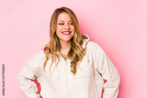 Young caucasian woman isolated on pink background laughs and closes eyes, feels relaxed and happy.