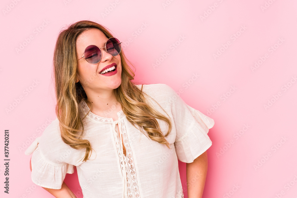 Young caucian woman with glasses isolated on pink background relaxed and happy laughing, neck stretched showing teeth. Young caucian woman with glasses isolated on pink background relaxed and happy laughing, neck stretched showing teeth.