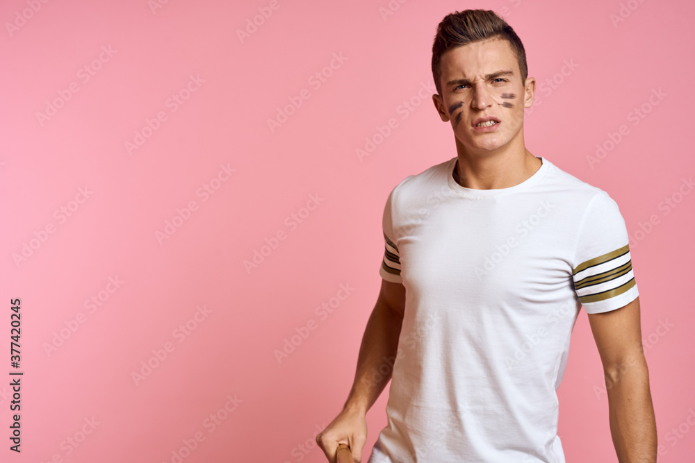 Energetic man with a bat on a pink background T-shirt face make-up black lines aggression model Energetic man with a bat on a pink background T-shirt face make-up black lines aggression model
