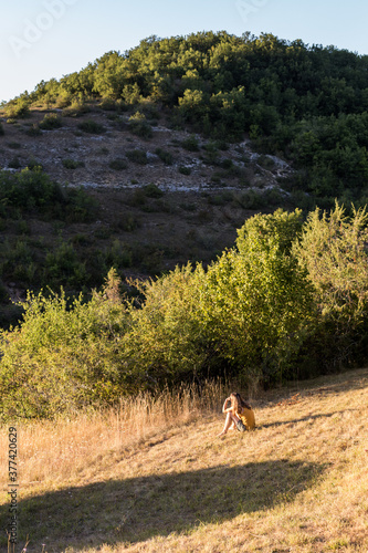 femme assise sur une colline au coucher de soleil