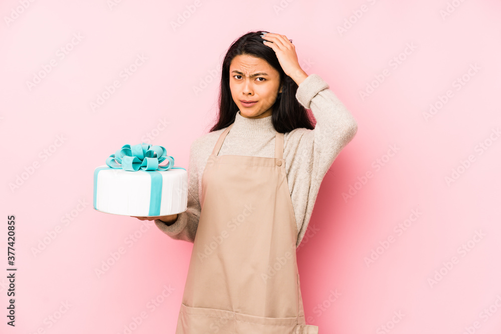 Young chinese woman holding a cake isolated pointing upside with opened mouth. Young chinese woman holding a cake isolated pointing upside with opened mouth.
