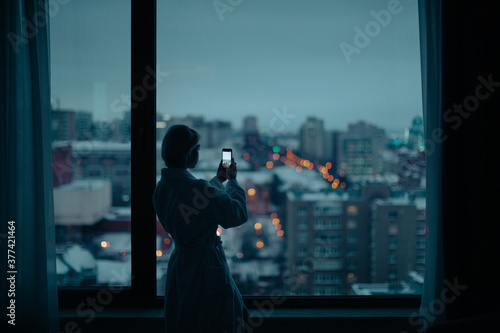 young woman near the window with cell phone photo