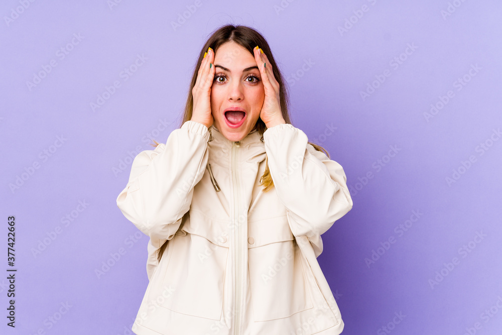 Young caucasian woman isolated on purple background having fun covering half of face with palm. Young caucasian woman isolated on purple background having fun covering half of face with palm.