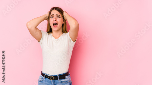 Young caucasian woman isolated on pink background screaming with rage.