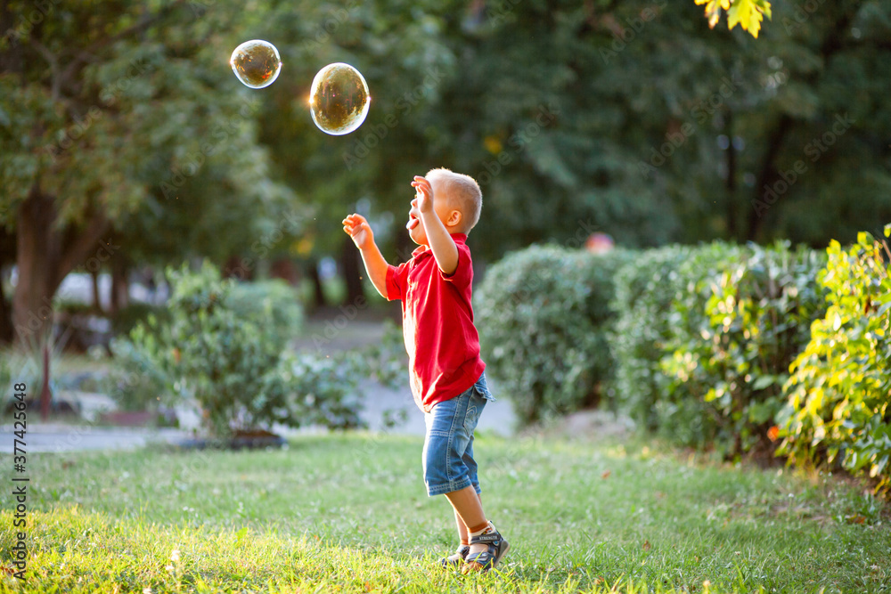 Little cute boy with Down Syndrome plays with huge soap bubbles in the