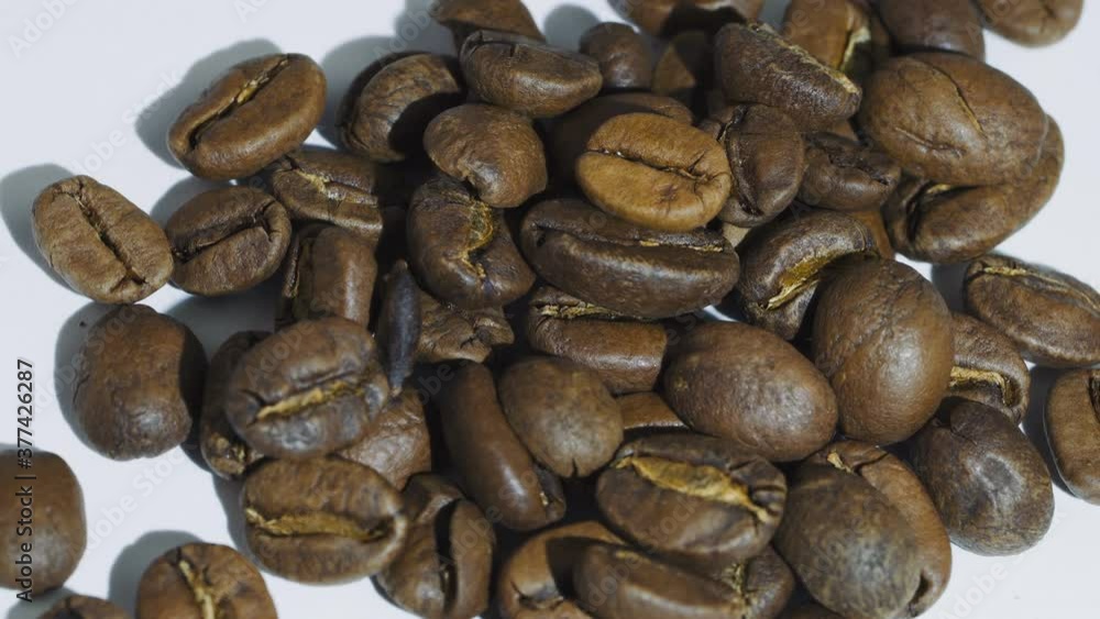 Dark Coffee beans rotating. Close up of roasted coffee beans on white background. Shallow depth of field Dark Coffee beans rotating. Close up of roasted coffee beans on white background. Shallow depth of field