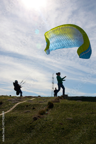 man trying to control the paraglide with friends and an antenna