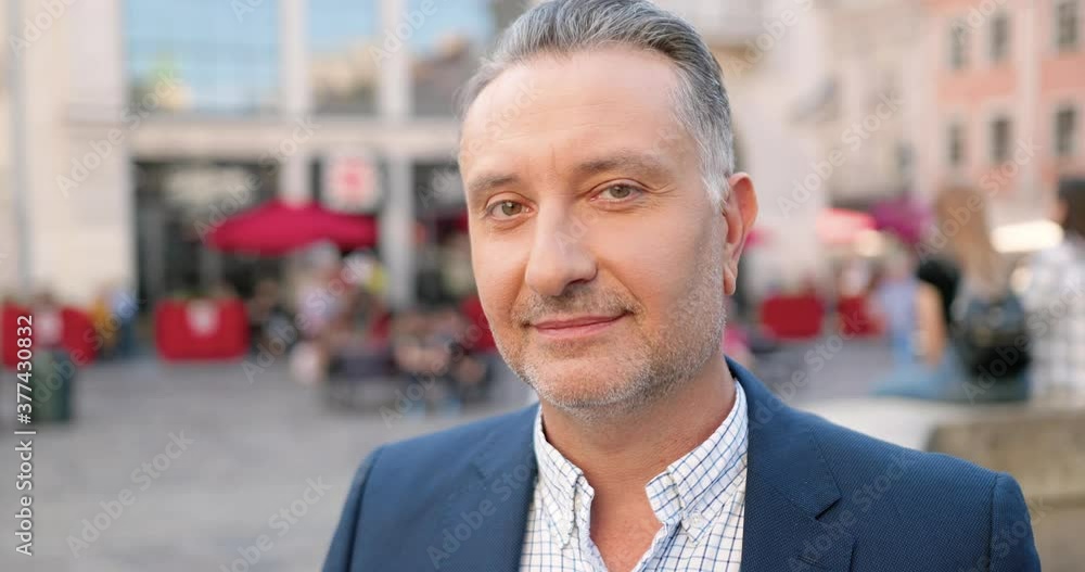 Portrait shot of Caucasian handsome middle-aged man looking at camera at street. Business look concept. Outdoors. Close up of male businessman smiling in town. Portrait shot of Caucasian handsome middle-aged man looking at camera at street. Business look concept. Outdoors. Close up of male businessman smiling in town.