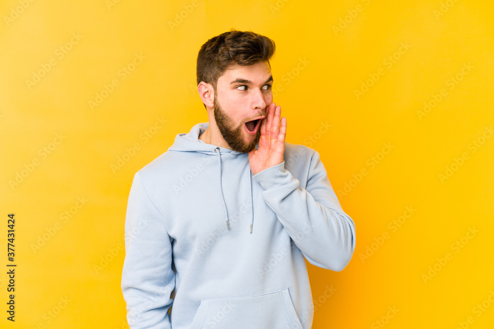 Young caucasian man isolated on yellow background is saying a secret hot braking news and looking aside Young caucasian man isolated on yellow background is saying a secret hot braking news and looking aside