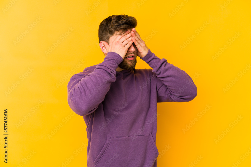 Young caucasian man isolated on yellow background afraid covering eyes with hands. Young caucasian man isolated on yellow background afraid covering eyes with hands.