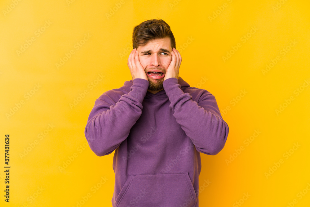Young caucasian man isolated on yellow background crying, unhappy with something, agony and confusion concept. Young caucasian man isolated on yellow background crying, unhappy with something, agony and confusion concept.
