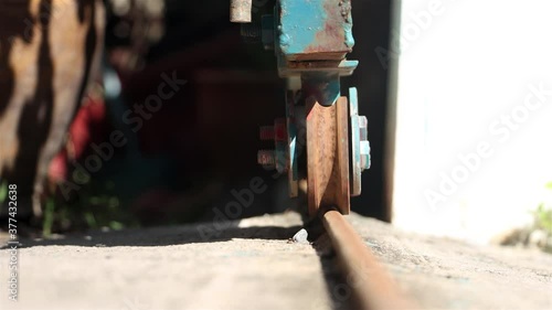 The opening a metal gate by riding of wheel on the rail. A rusted wheel from sliding gate on a rail, close up view.