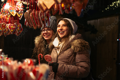 Smiling woman choosing candies with her female friend at the Christmas market © Daniel