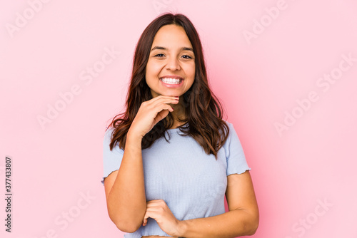 Young mixed race hispanic woman isolated smiling happy and confident, touching chin with hand. © Asier