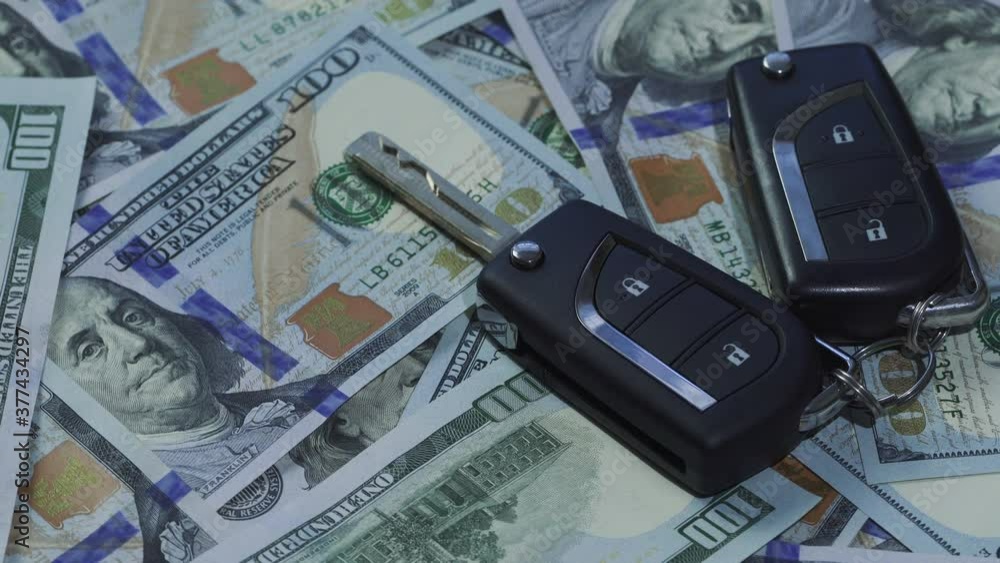 Close-up of car keys on stack of hundred dollar bills rotating. Buying car concepts. Close-up of car keys on stack of hundred dollar bills rotating. Buying car concepts.