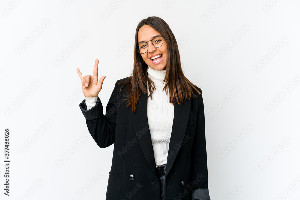 Young mixed race business woman isolated on white background showing a horns gesture as a revolution concept. Young mixed race business woman isolated on white background showing a horns gesture as a revolution concept.
