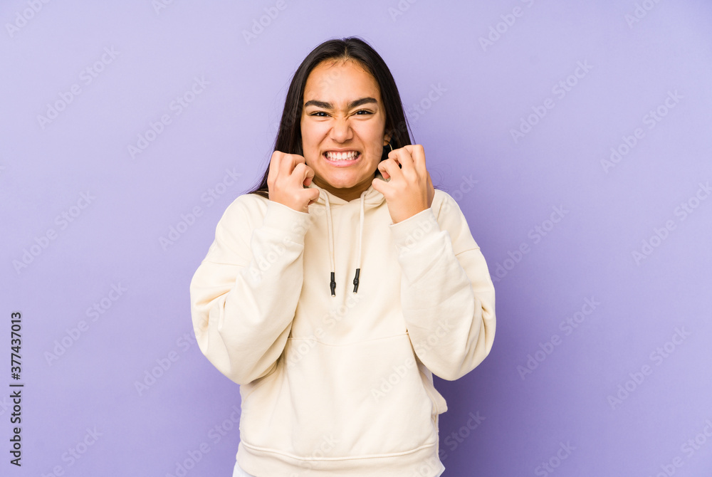 Young woman isolated on a purple background upset screaming with tense hands. Young woman isolated on a purple background upset screaming with tense hands.