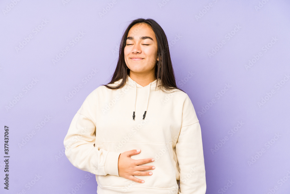 Young woman isolated on a purple background touches tummy, smiles gently, eating and satisfaction concept. Young woman isolated on a purple background touches tummy, smiles gently, eating and satisfaction concept.