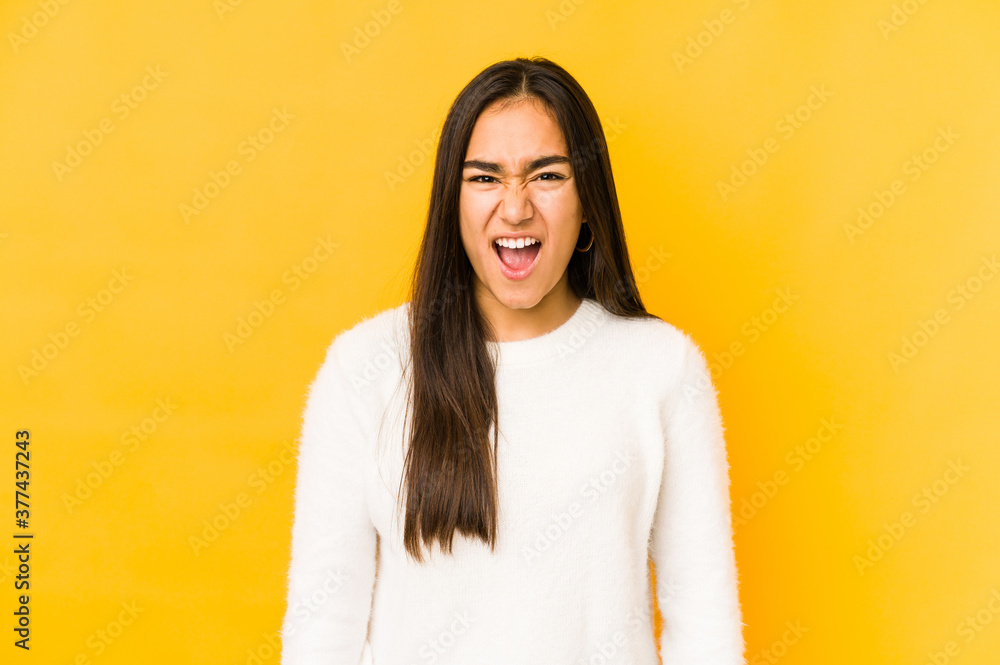 Fototapeta premium Young woman isolated on a yellow background screaming very angry and aggressive.