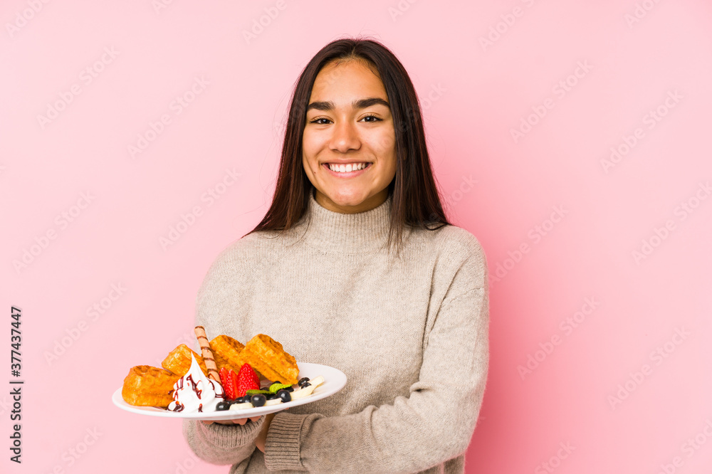 Young asian woman holding a waffle isolated laughing and having fun. Young asian woman holding a waffle isolated laughing and having fun.