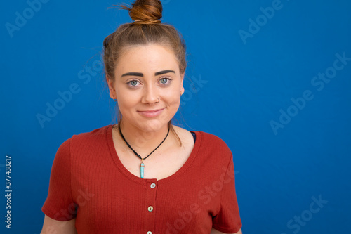 young woman with bun looking at camera against blue background
